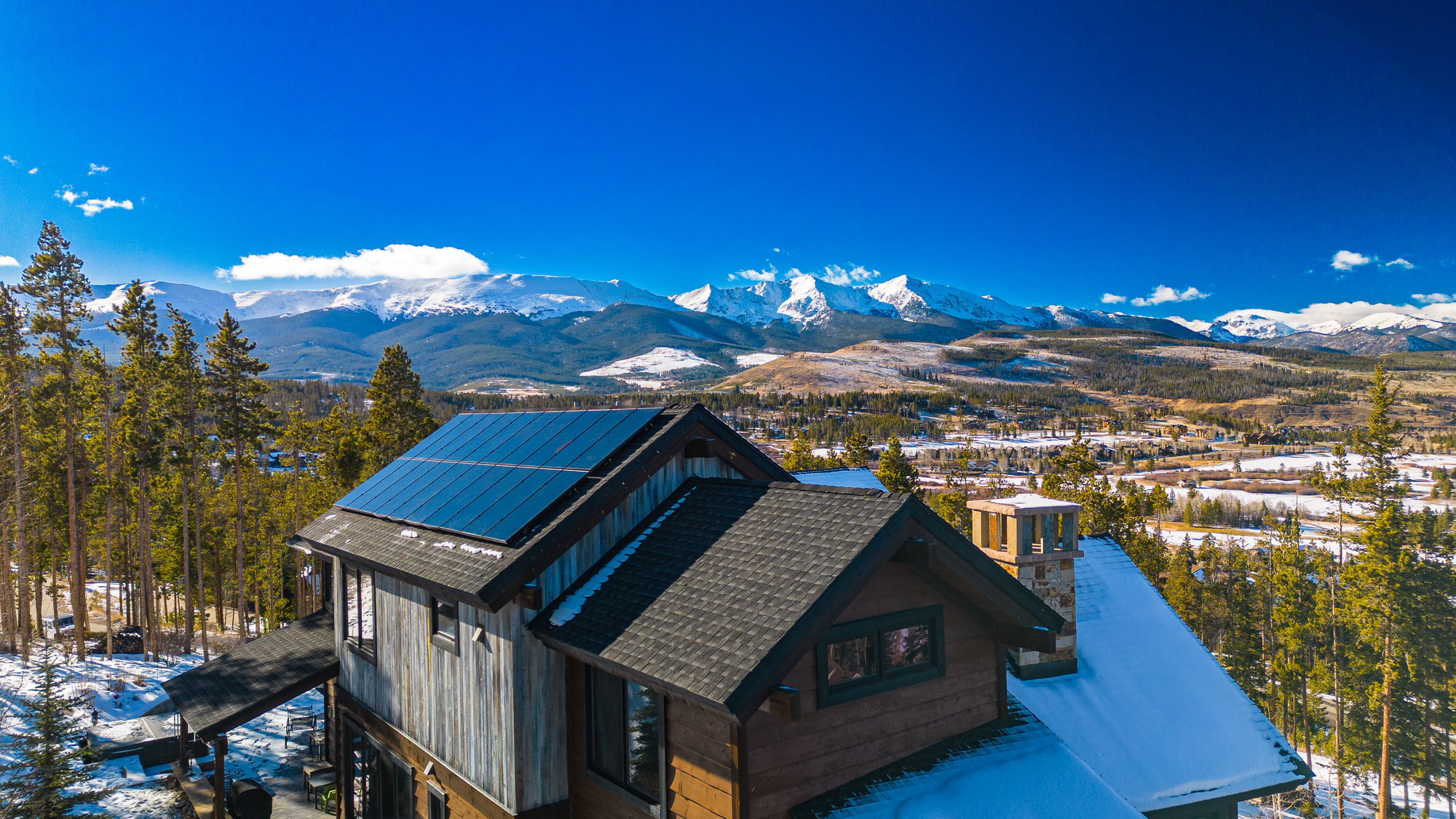 Picture of home with solar panels on the roof and mountains in the background.